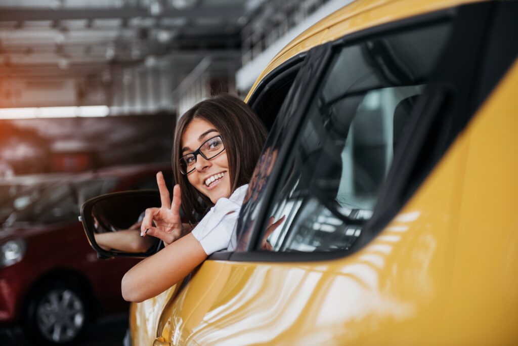 Young woman in her new car smiling